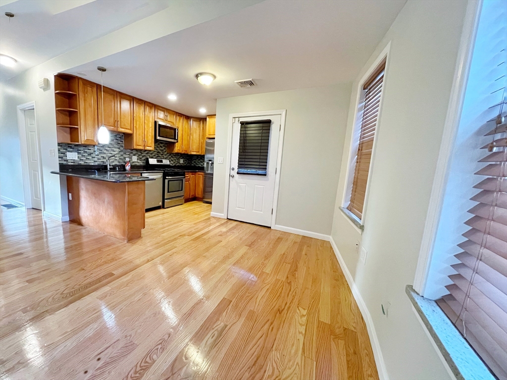 88-90 George Street Boston, MA 02119 - Photo 5 of 15 a view of a living room with kitchen island granite countertop wooden floor and a flat screen tv