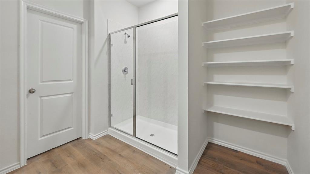 232 Pheasant Run Road Terrell, TX 75160 - Photo 4 of 36 Glass-enclosed shower with a white base, surrounded by wood-finish flooring and multiple built-in shelving units