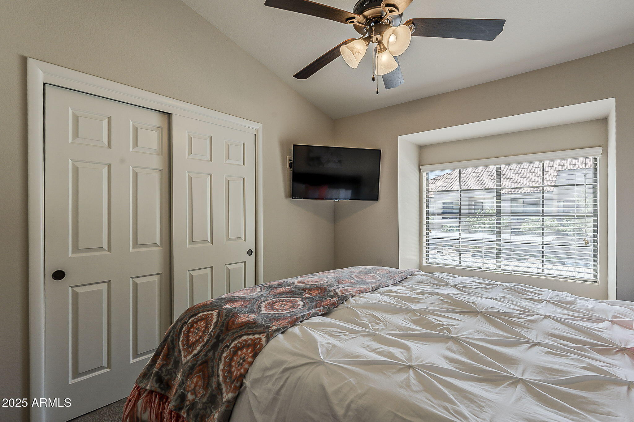 9707 East Mountain View Road, Unit 2412 Scottsdale, AZ 85258 - Photo 31 of 43 a bedroom with a large bed and a flat tv screen