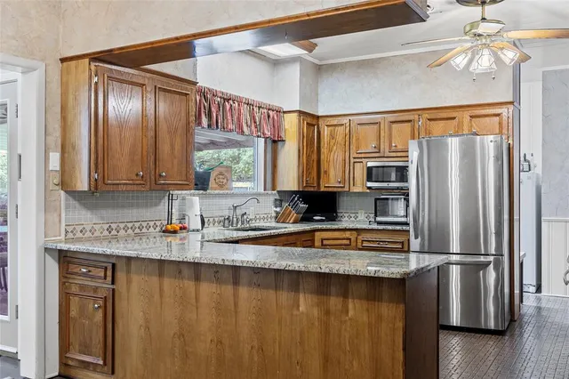 a kitchen with stainless steel appliances granite countertop a refrigerator a stove and a sink with wooden floor