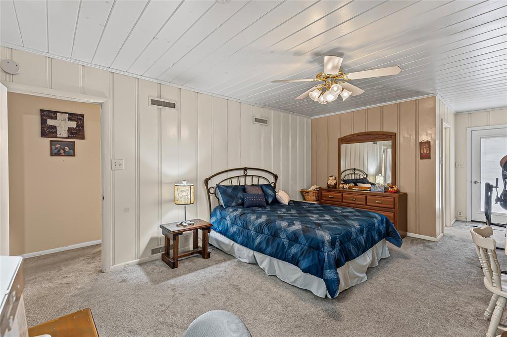 1302 Culver Street Commerce, TX 75428 - Photo 25 of 40 a spacious bedroom with two beds and a chandelier