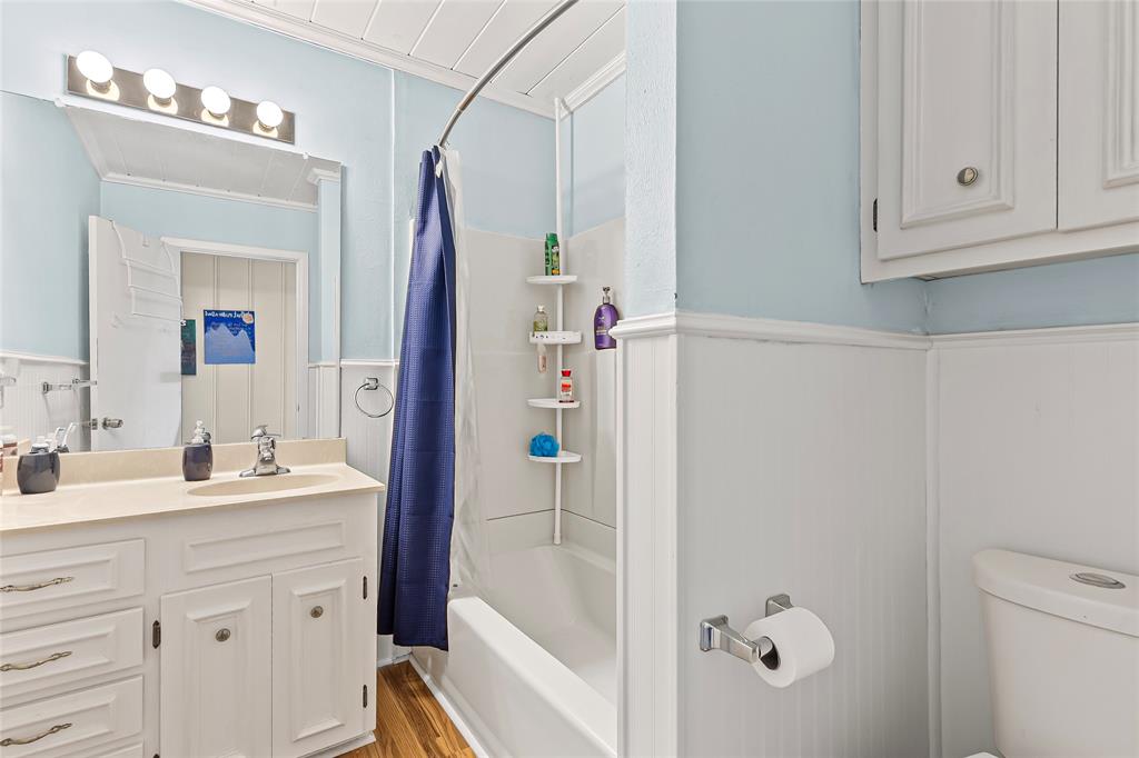 1302 Culver Street Commerce, TX 75428 - Photo 28 of 40 a bathroom with a sink vanity granite tub and a mirror