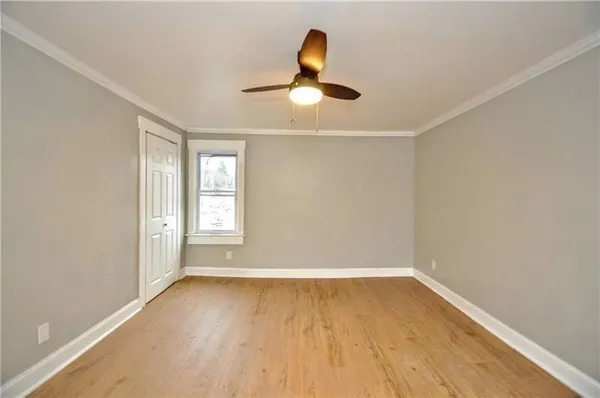 a view of empty room with wooden floor and fan