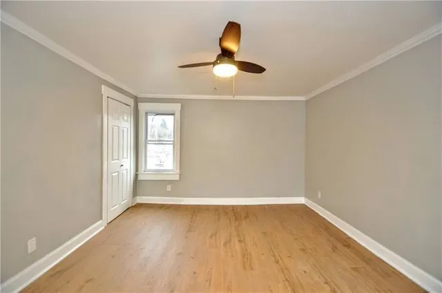 a view of empty room with wooden floor and fan