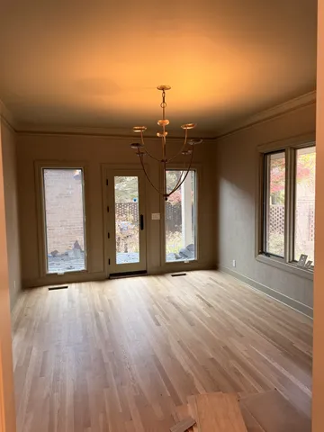 a view of an empty room with window and wooden floor