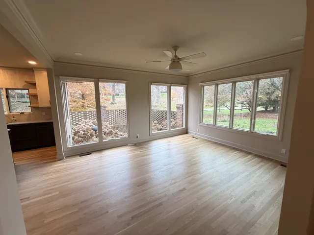 a view of an empty room with a window and wooden floor