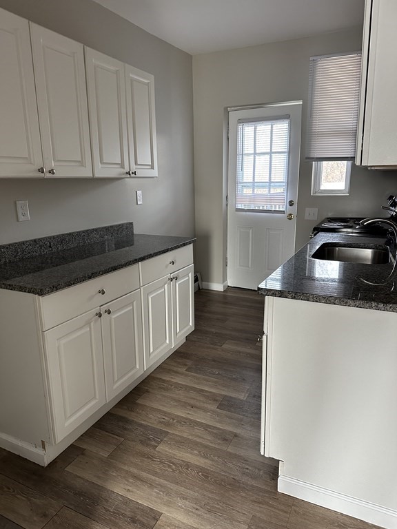 41-49 Belmont Avenue Springfield, MA 01108 - Photo 17 of 18 a kitchen with granite countertop a sink dishwasher a stove and white cabinets with wooden floor
