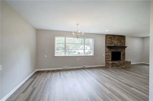 an empty room with windows a fireplace and wooden floor