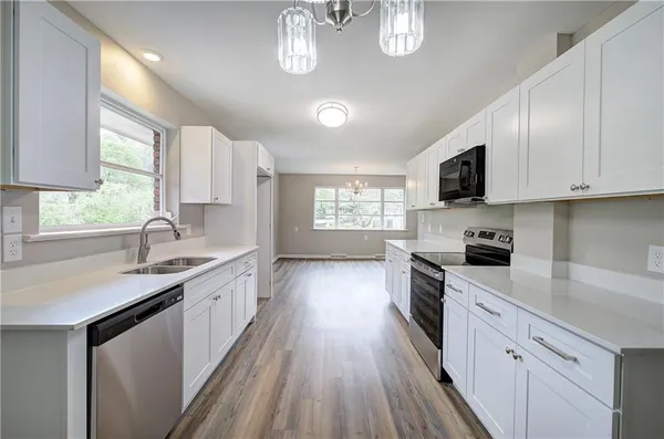 a kitchen with granite countertop a sink a counter space appliances and cabinets