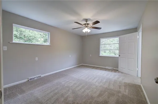 an empty room with windows and ceiling fan