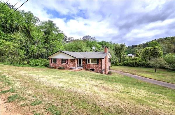 a view of a house with a big yard and large trees