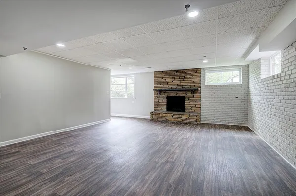an empty room with wooden floor fireplace and windows
