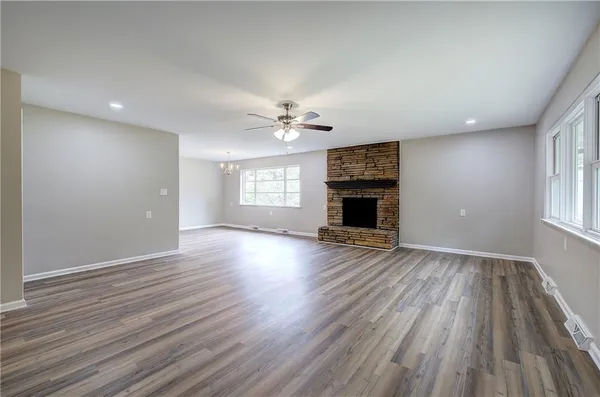 an empty room with wooden floor fireplace and windows