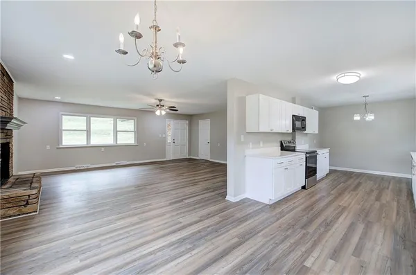 a kitchen with stainless steel appliances granite countertop a stove top oven a sink dishwasher and a white cabinets with wooden floor