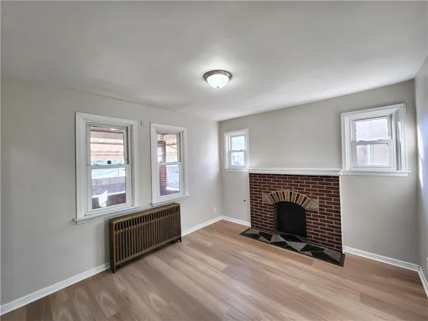 an empty room with wooden floor a fireplace and windows