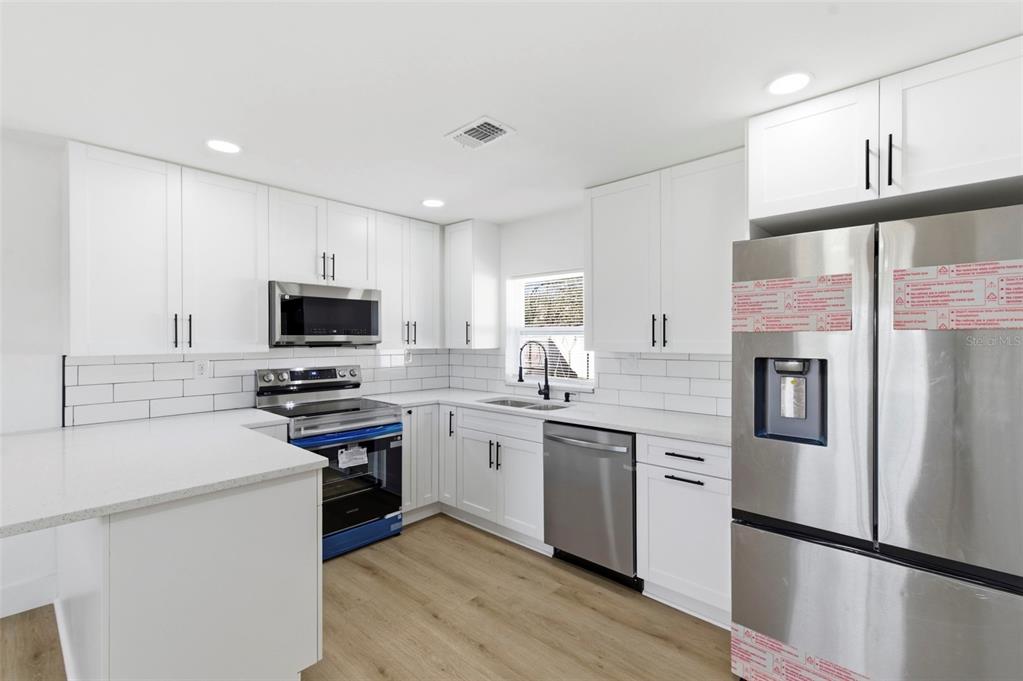 1448 South Belcher Road Largo, FL 33771 - Photo 13 of 47 a kitchen with stainless steel appliances a stove refrigerator sink and microwave