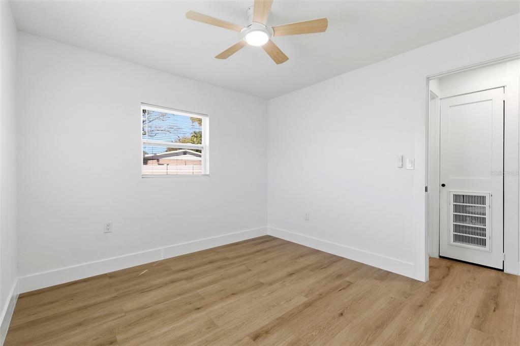 1448 South Belcher Road Largo, FL 33771 - Photo 29 of 47 an empty room with wooden floor chandelier fan and windows