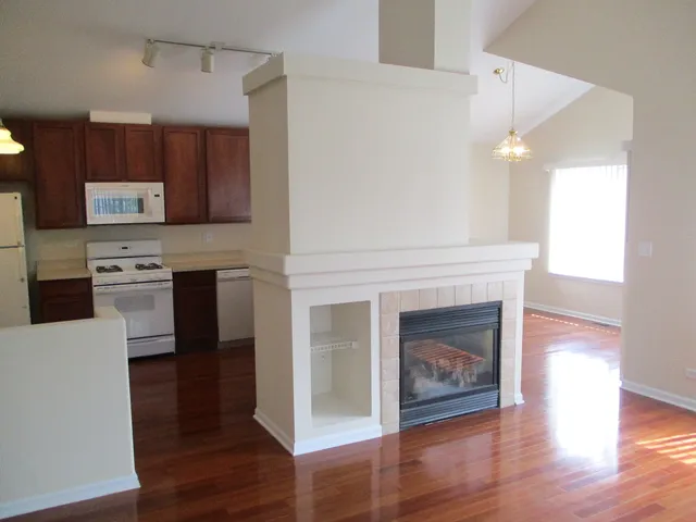 a living room with stainless steel appliances wooden floor and a fireplace