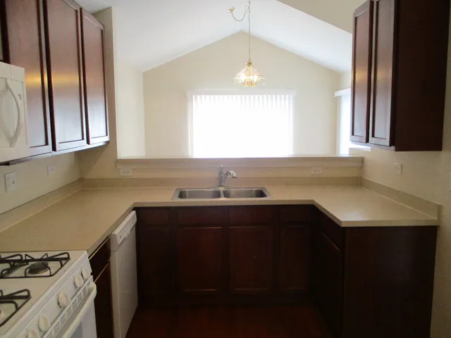 a kitchen with stainless steel appliances a sink dishwasher a stove and a refrigerator with wooden floor