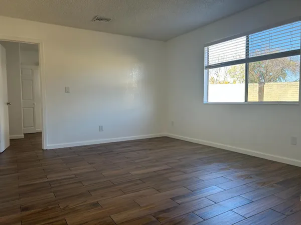 a view of an empty room with wooden floor and a window