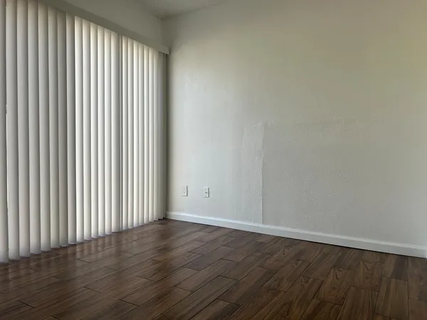 a view of an empty room with wooden floor and a window