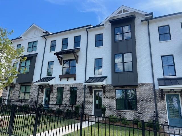 629 Silva Street, Unit 128 Cumming, GA 30040 - Photo 4 of 54 a view of a brick house with large windows and a small yard