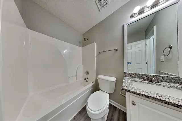 a bathroom with a granite countertop toilet a sink and a bathtub