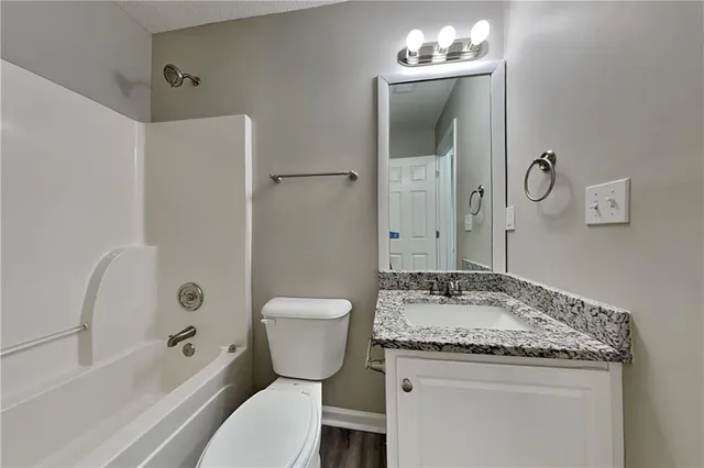 a bathroom with a granite countertop sink toilet and shower