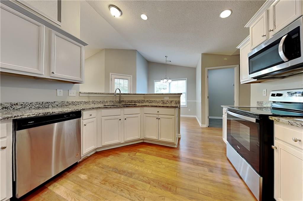 3762 Plymouth Rock Drive Loganville, GA 30052 - Photo 6 of 28 a kitchen with stainless steel appliances granite countertop a stove a sink and white cabinets