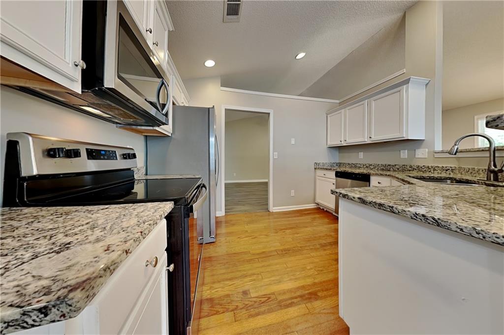 3762 Plymouth Rock Drive Loganville, GA 30052 - Photo 7 of 28 a kitchen with stainless steel appliances granite countertop a stove a sink and a refrigerator