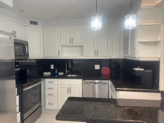 a kitchen with granite countertop a sink a stove and cabinets