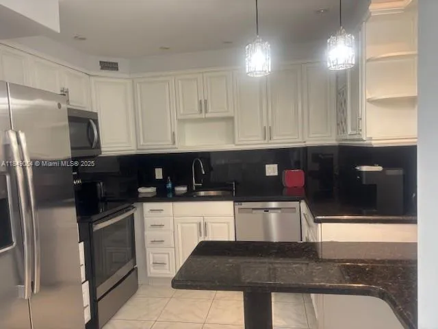 a kitchen with stainless steel appliances granite countertop a stove a microwave and a refrigerator