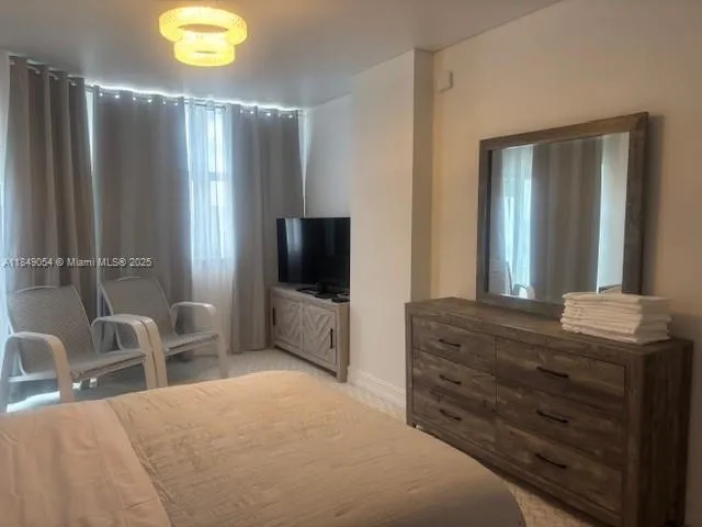a bedroom with a bed and a flat tv screen on dresser
