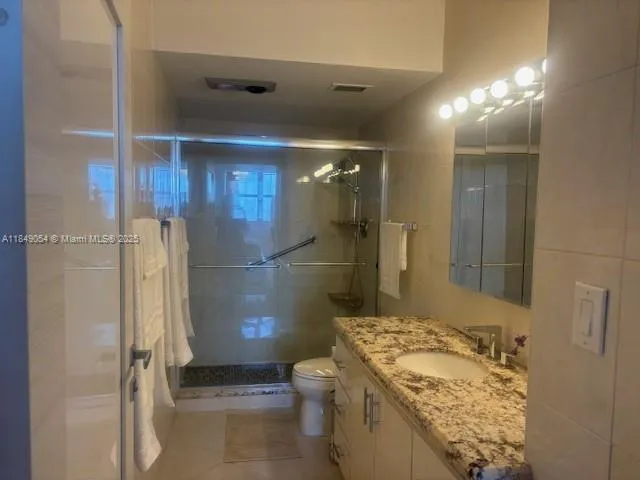 a bathroom with a granite countertop sink a toilet and shower