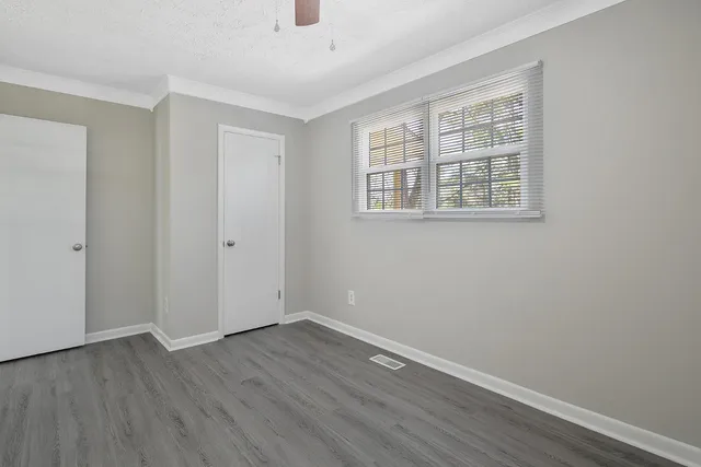 an empty room with wooden floor and windows