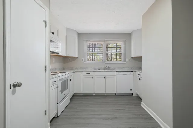 a kitchen with granite countertop white cabinets and white appliances