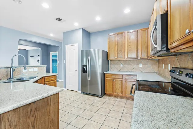 a kitchen with stainless steel appliances granite countertop a sink and dishwasher a refrigerator with wooden cabinets