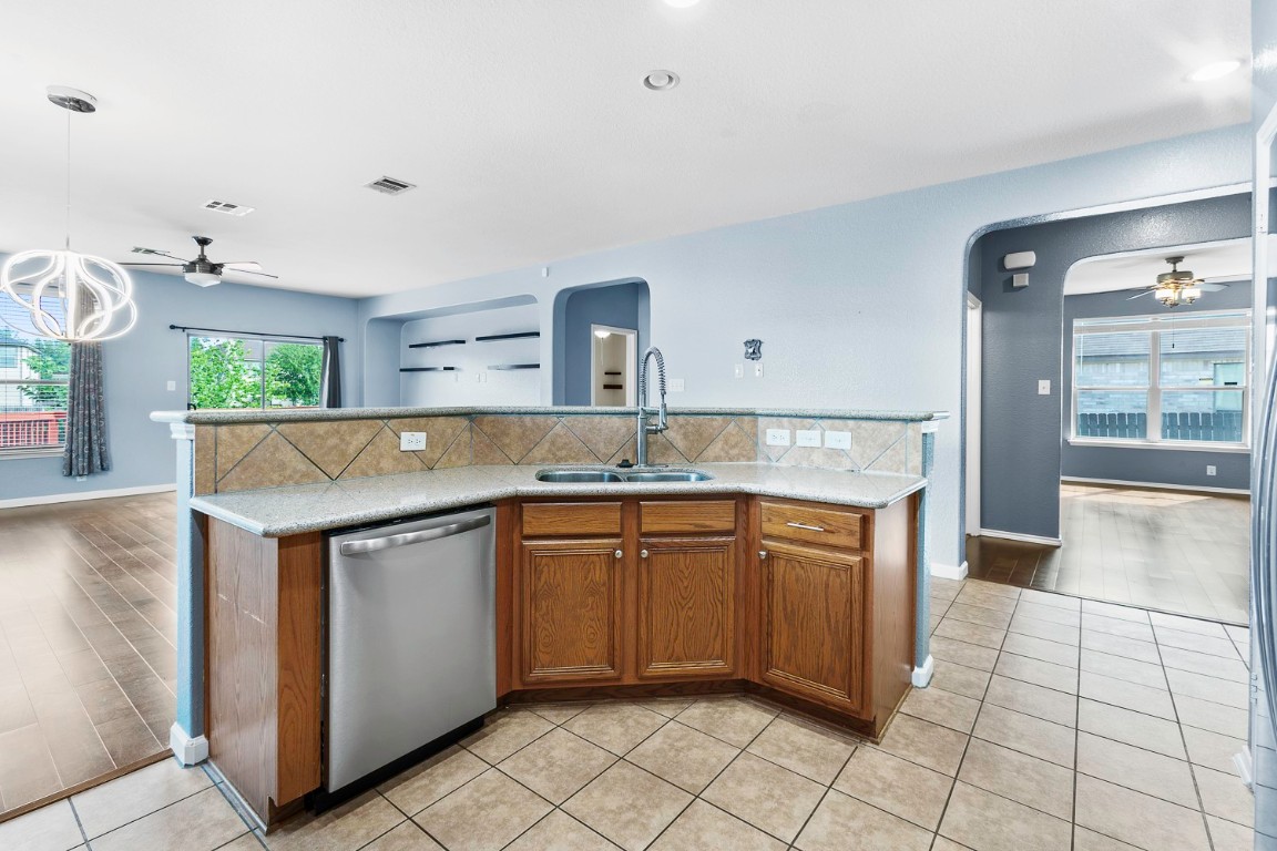 345 Apricot Drive Kyle, TX 78640 - Photo 14 of 37 a kitchen with stainless steel appliances granite countertop a sink and dishwasher a stove top oven with wooden floor