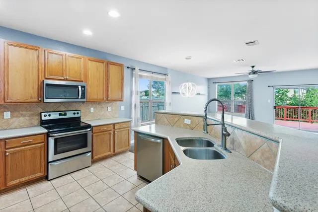a kitchen with stainless steel appliances granite countertop a sink a stove top oven a counter space and cabinets