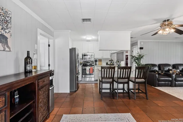 a open kitchen with stainless steel appliances kitchen island granite countertop a table chairs and a refrigerator
