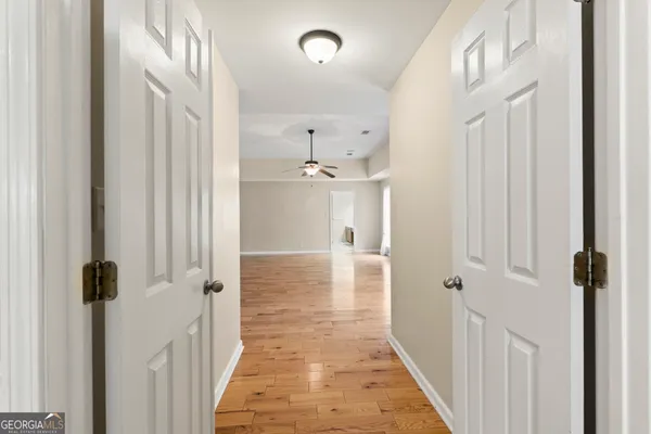 a view of empty room with wooden floor and fan