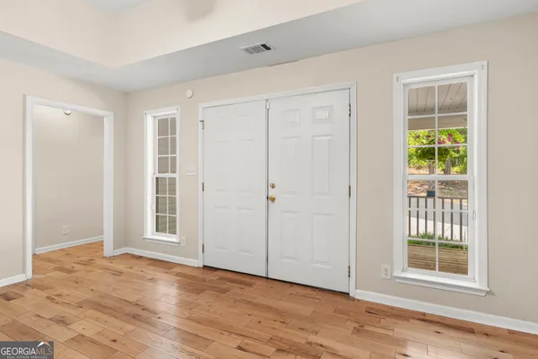 a view of an empty room with wooden floor and a window