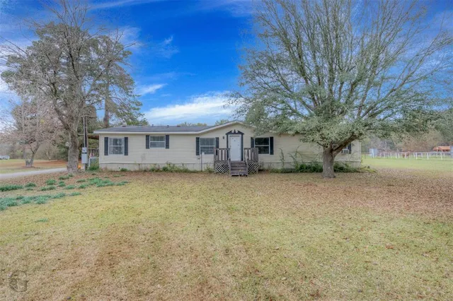 a view of a house with a large tree and a yard