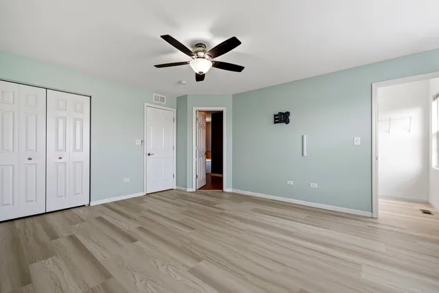 a view of empty room with wooden floor and ceiling fan
