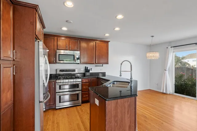 a kitchen with stainless steel appliances granite countertop a stove a sink a refrigerator and a microwave