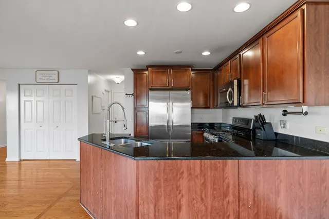 a kitchen with stainless steel appliances granite countertop a sink a stove and a refrigerator