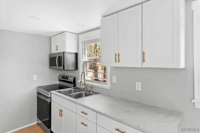 a kitchen with white cabinets and sink