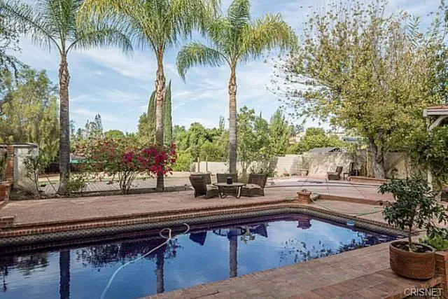 a swimming pool with outdoor seating and trees