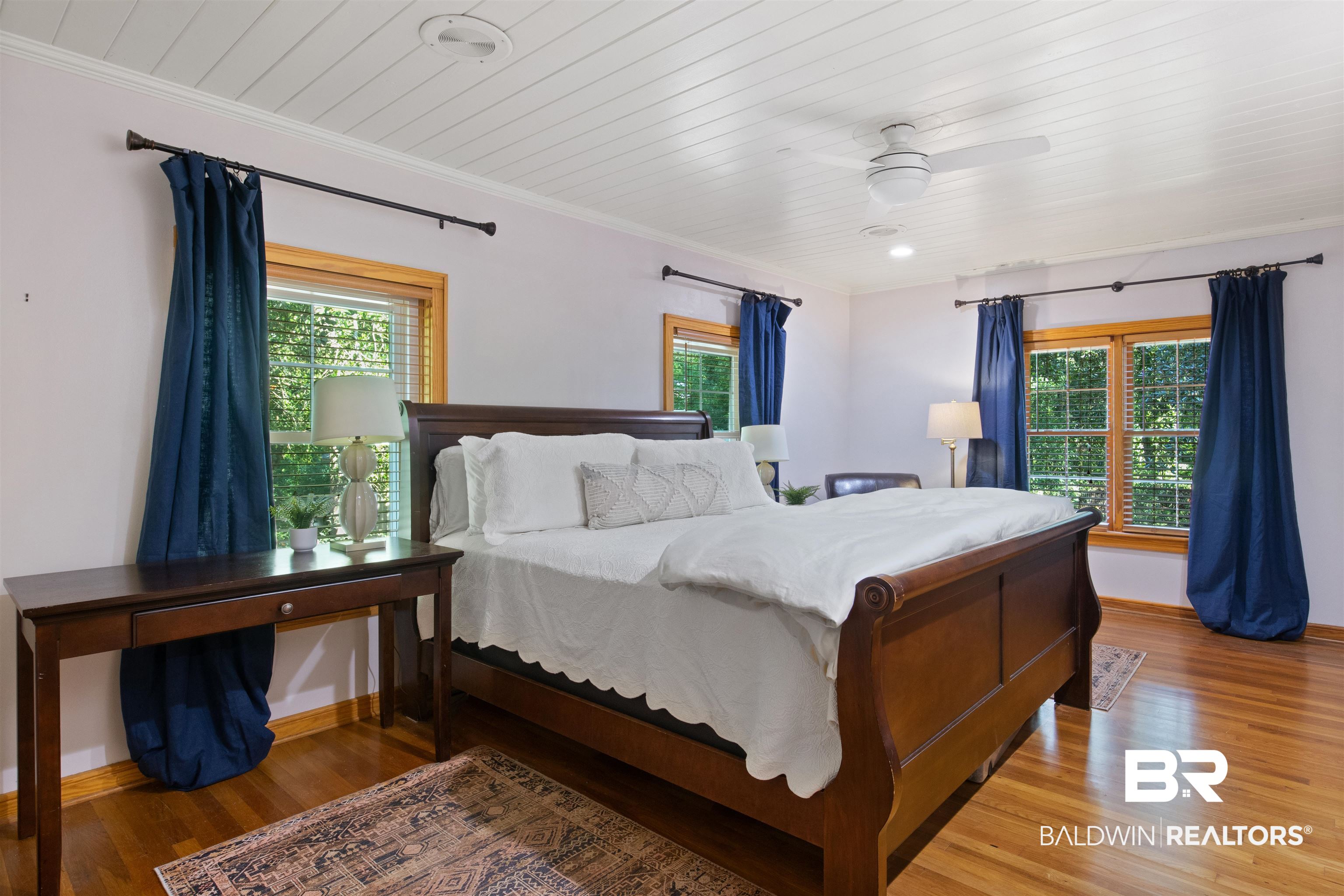 15100 Vasko Road Silverhill, AL 36576 - Photo 21 of 51 Bedroom featuring crown molding, remote controlled ceiling fan, and wood flooring. New windows overlook trees and path to the sawmill cabin on west side of property.