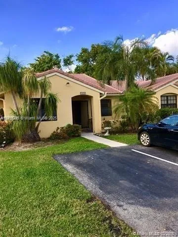 a view of a white house next to a yard and palm trees